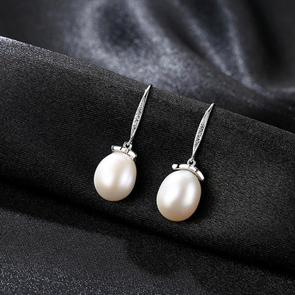 White natural pearl CZ leaf dangle earrings in rhodium-plated sterling silver on fabric.