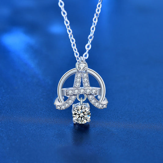 Close-up of Eiffel-inspired sterling silver necklace with moissanite and CZ accents on blue background.