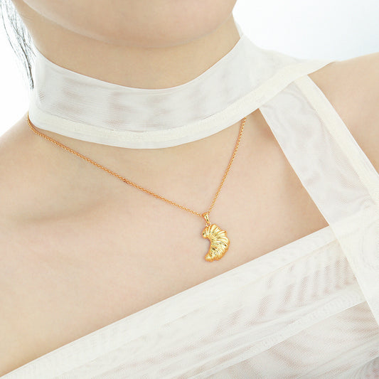 Model wearing a gold croissant pendant necklace on the collarbone