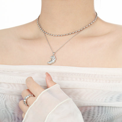 Model layering a sterling silver croissant pendant with a beaded choker