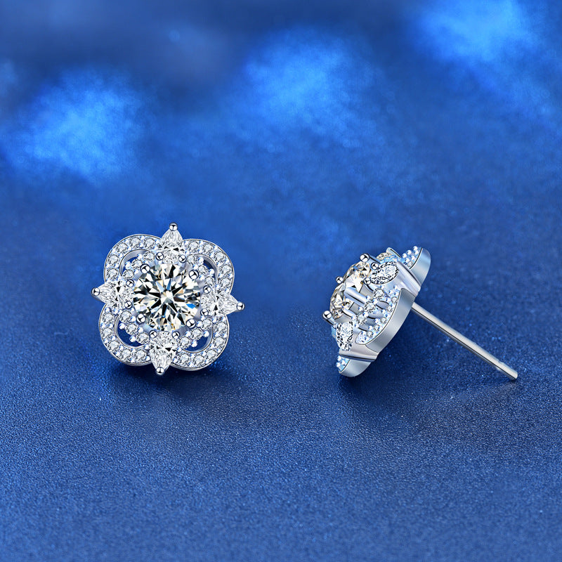 Pair of quatrefoil moissanite and CZ halo studs in sterling silver on blue background