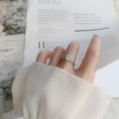 Moissanite starflower ring worn on hand, showcasing delicate floral halo and vintage milgrain in sterling silver