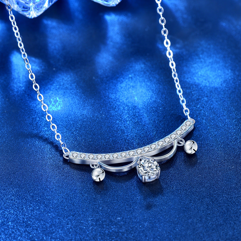 Angled close-up of lace arc moissanite tassel drop necklace in rhodium-plated sterling silver on blue surface.
