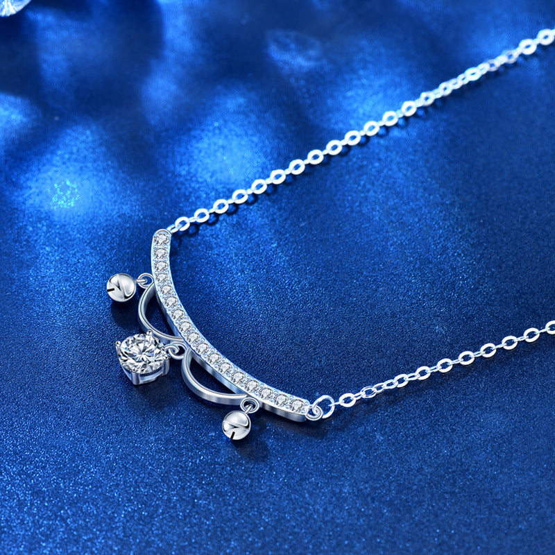 Close-up of CZ pavé arc with moissanite drop and tiny tassels on chain, blue textured background.