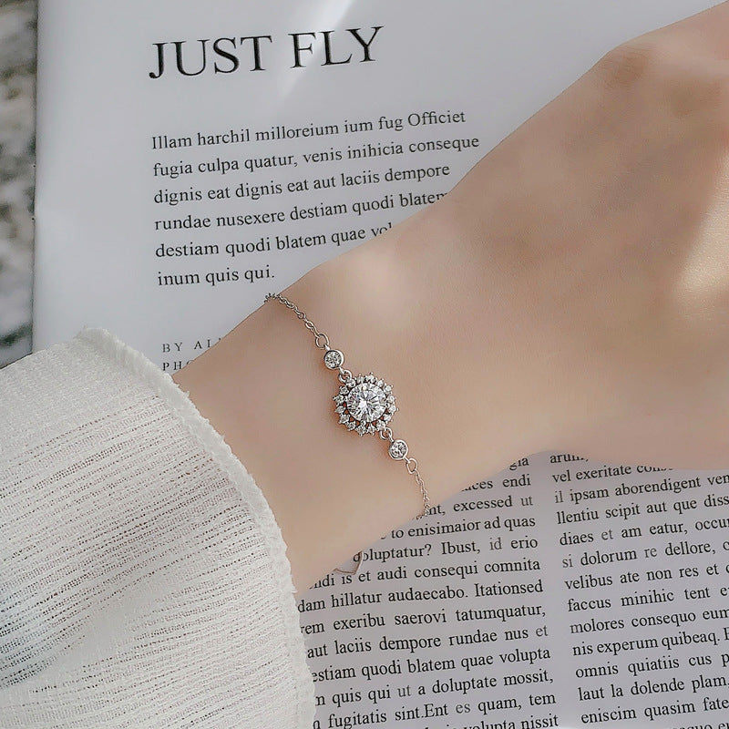 Model wearing sunflower moissanite bracelet on wrist on an open magazine background.